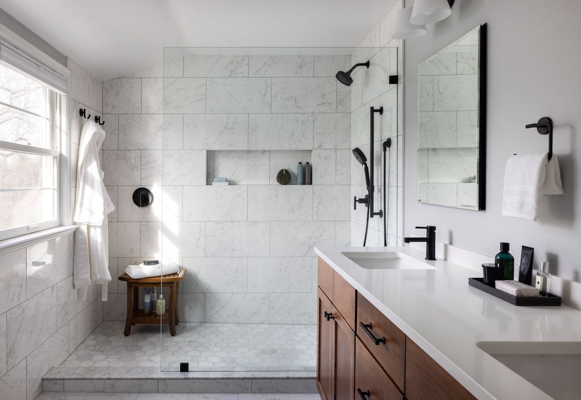 renovated bathroom with white walls, countertops, and shower tiles